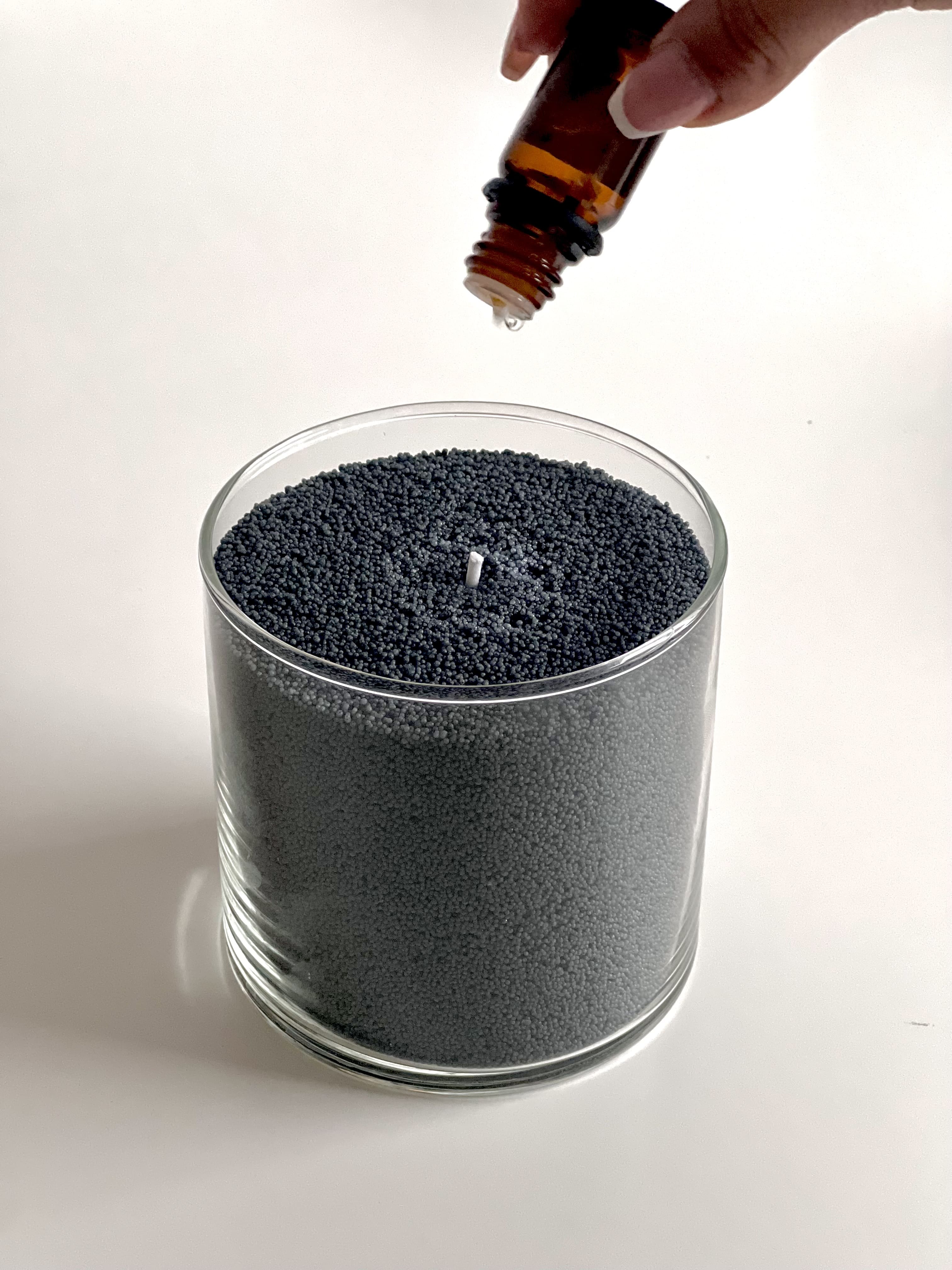 Ajout de gouttes d’huile parfumée sur une bougie perlée Lumea dans un verre transparent – personnalisation olfactive simple et naturelle.
