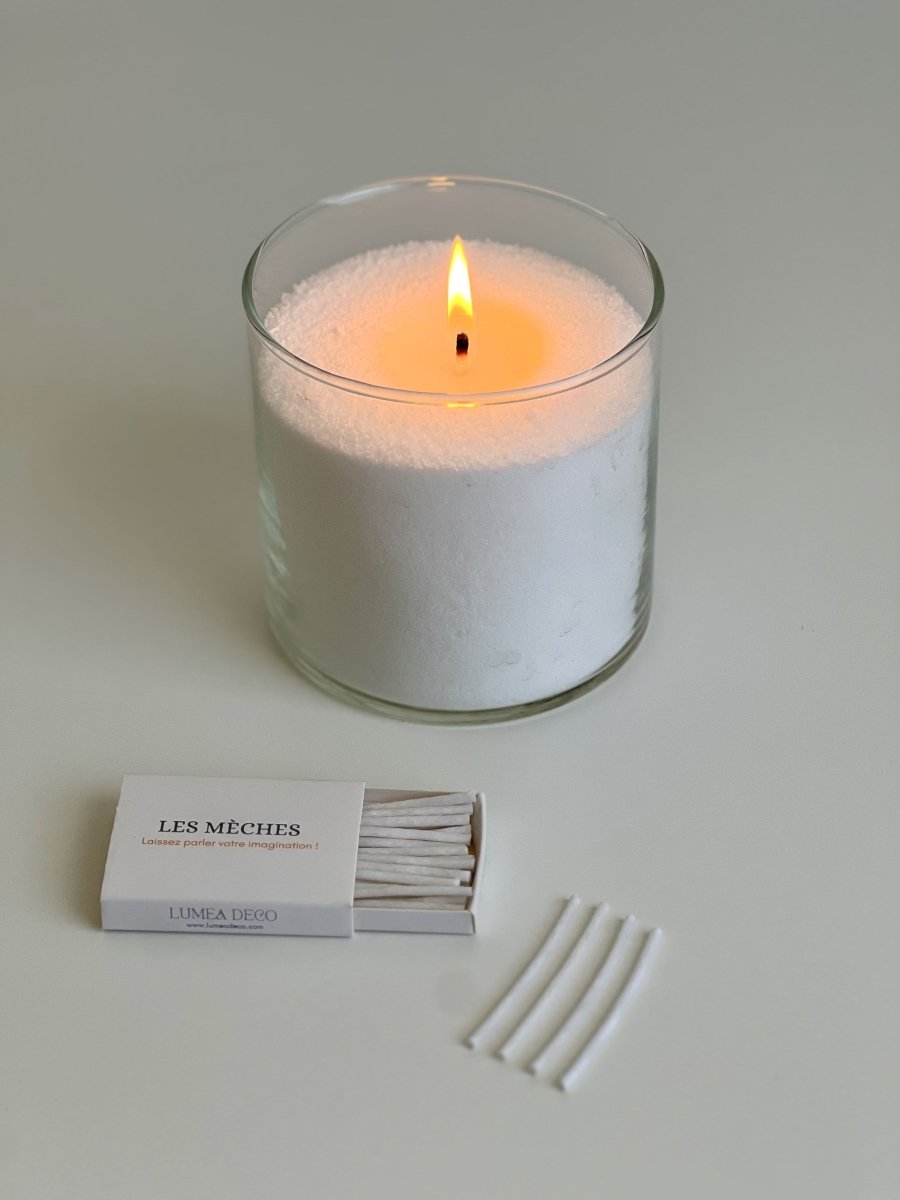 Bougie perlée blanche Lumea allumée dans un contenant en verre, accompagnée de mèches en coton et d’une boîte d’accessoires – concept rechargeable, naturel et personnalisable.