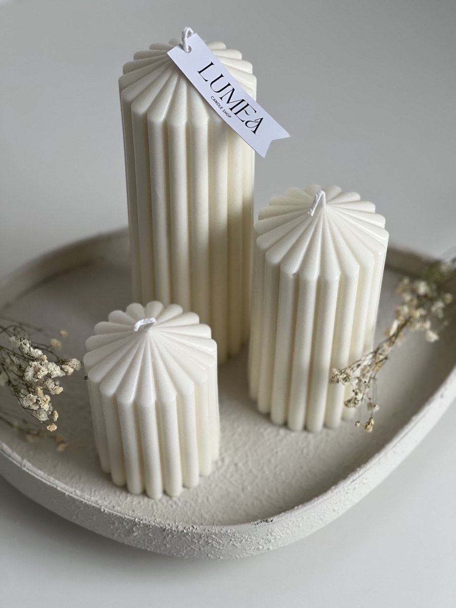 Trio de bougies pilier blanches à rainures torsadées, posées sur un plateau en béton beige, accompagnées de fleurs séchées, design minimaliste signé Lumea Deco.