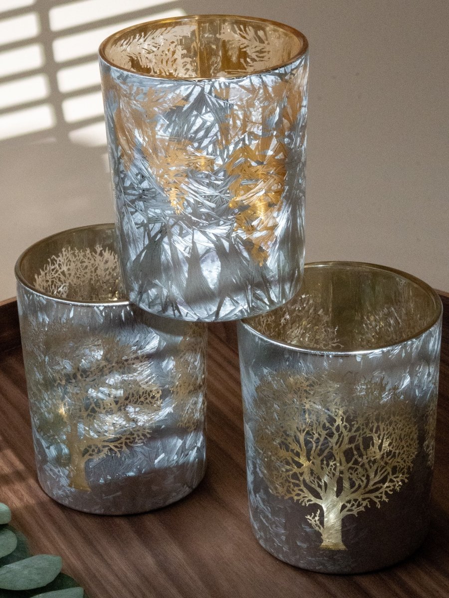 Trio de photophores argentés avec reflets givrés et motifs dorés d’arbres et de feuillages – objets déco pour créer une ambiance cosy, hivernale et élégante.