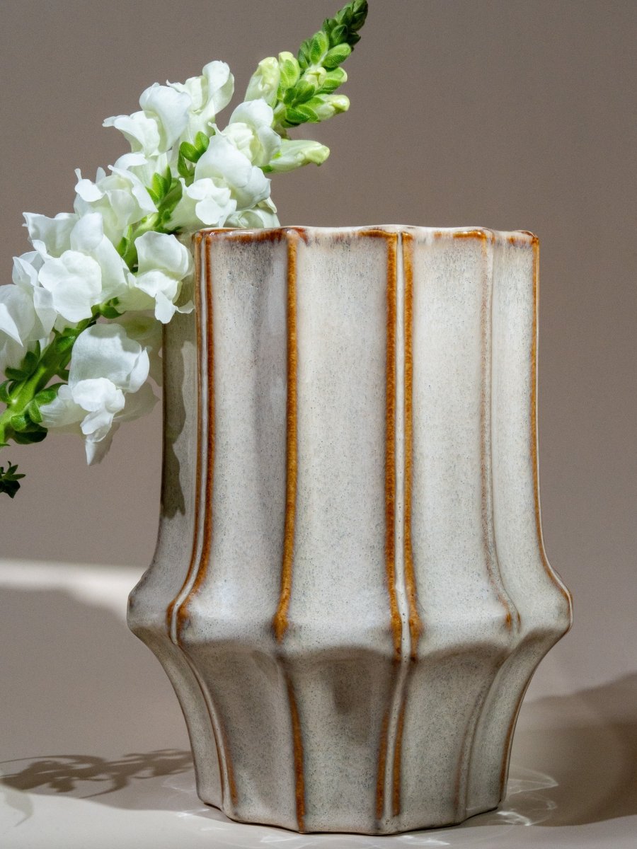 Vase en céramique blanche à rainures verticales et effet brut, finition artisanale, parfait pour accueillir des fleurs ou décorer un intérieur naturel et authentique.