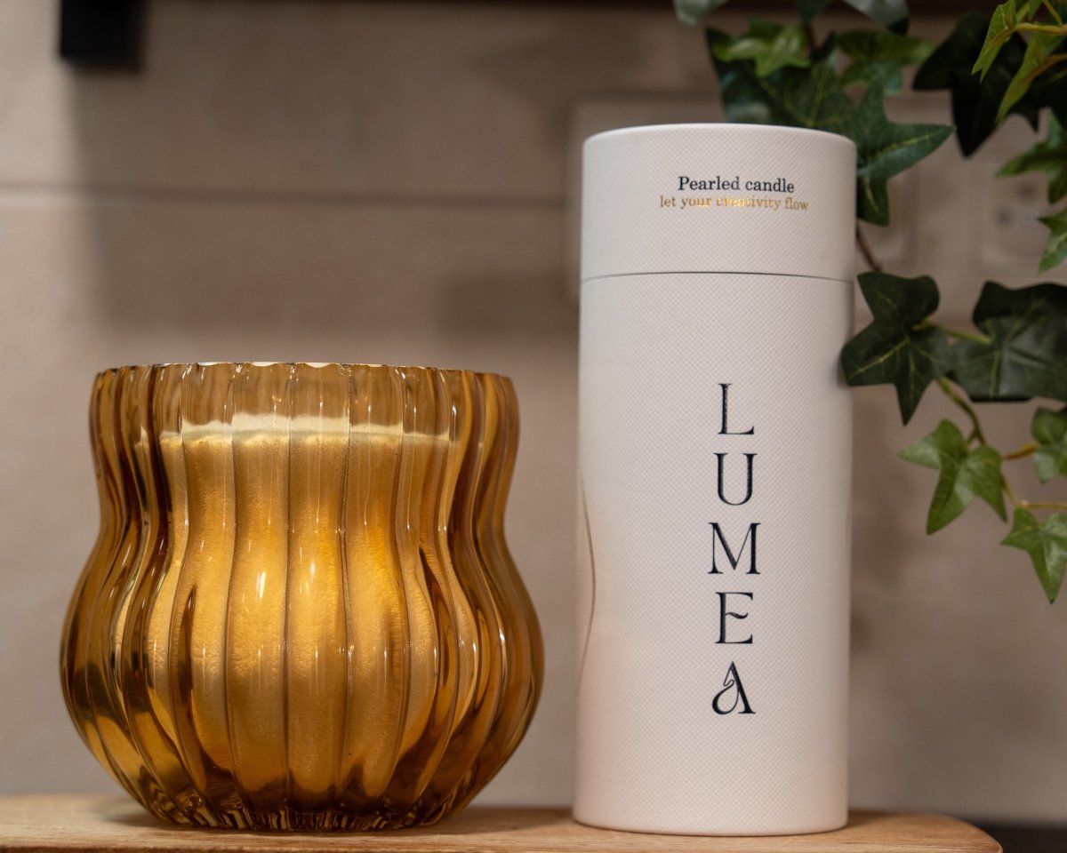 Vase en verre ambré strié en forme galbée, contenant une bougie perlée Lumea avec son tube blanc en arrière-plan – décoration chaleureuse et élégante, parfaite à offrir.