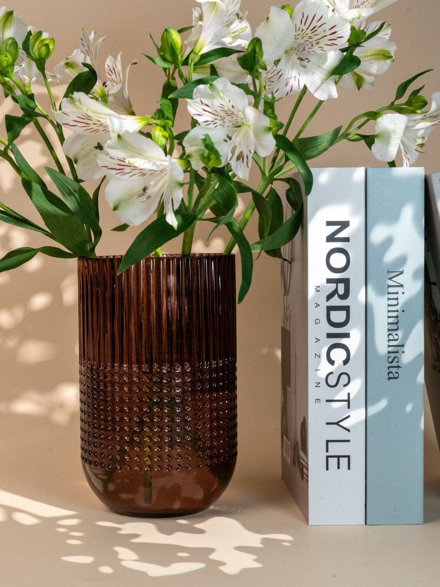 Vase en verre transparent à reliefs texturés avec motifs en pois et stries verticales, contenant un bouquet de fleurs blanches – idéal pour une décoration raffinée ou un cadeau élégant.